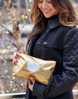 Women smiling holding a gold silver heart clutch