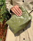 Person holding an olive green fabric pouch with star pattern against a natural background
