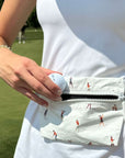 Person putting golf ball into layflat fanny pack belt bag in golfers pattern