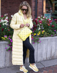 Women in long yellow jacket outdoors holding medium zipper pouch in yellow bandana print