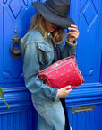 Person holding a red clutch in front of a blue door