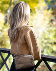 Person outdoors looking at scenery wearing mini puffer chain purse in shimmer bronze