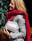 A woman wearing a gray jacket and a red patterned scarf carries a silver puffer crossbody bag with a chain strap.