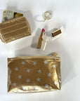 Mini zipper pouch in gold with myriad of stars and puffer wallet in gold with accessories on white background