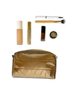 Bronze makeup pouch with various cosmetic items on a white background