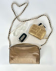 Bronze handbag with gold chain metal purse strap with reading glasses, gold wallet and keys on a white background