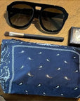 Mini Zipper Pouch Navy Blue Bandana Print with Sunglasses, makeup brush, and compact on a wooden surface.