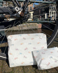Pouch set in white with colorful bicycles pattern sitting against bicycle tire