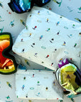 White skier and goggles pattern zipper pouch laying next to ski goggles