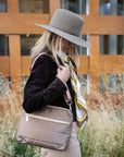 Woman outdoors wearing bronze puffer purse and western hat