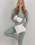 Woman in green athletic wear holding two yoga print pouches against a plain background