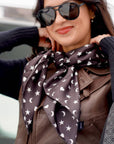 Woman wearing Signature Silk Scarf in black with white hearts, moons, and stars tied around the neck