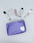 Purple pouch with a heart design, surrounded by skincare products on a light gray background