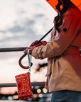 Women with orange umbrella carrying orange bandana print wristlet near canal