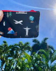 Little zipper wallet with landmarks from the seven continents set against a blue sky and palm trees.