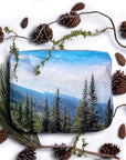 Medium zipper pouch depicting the top of a mountain with evergreen trees on white background with pinecones