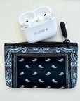 Black bandana patterned pouch with white airpods case labeled 'HI LOVE' on a light gray background