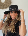 Woman wearing the black Signature scarfette with white hearts, moons and stars wrapped as a hat band around a black western hat.