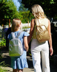 Mother and daughter holding hands wearing coordinated gold and silver backpacks