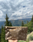 Small shimmer bronze cosmetic pouch with stars in front of mountains and trees