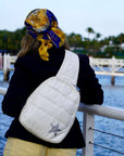 Person with a white bag and colorful headscarf by a waterfront