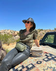 Woman in desert sitting on car wearing Puffer Crossbody Fanny Pack Belt Bag in Shimmer Olive Green