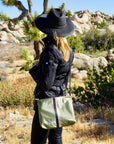 Woman standing in Joshua Tree wearing shimmer olive green crossbody purse