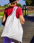 Person walking on a wooden boardwalk with a golfer patterned bag over their shoulder