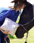 Woman kissing a horse while holding shimmer beige equestrian zipper pouch