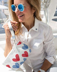 Woman on a boat holding a pouch with red and blue heart patterns