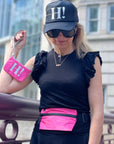 Woman wearing hot pink fanny pack and holding hot pink wristlet