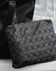 Black signature medium zipper pouch with tonal Hi Love monogram print styled next to a matching black travel bag.