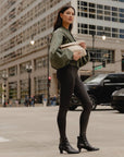 Woman carrying Medium Pouch Signature Shimmer Beige folded as a clutch while standing on a city street.