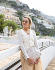 Woman standing along Italy coast holding medium shimmer beige with stars zipper clutch