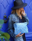 Woman holding a blue bandana clutch in front of a blue door.