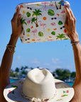 Person holding a colorful pouch with tropical patterns against a clear blue sky.