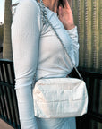 Woman wearing shimmer white mini puffer purse with chain strap over shoulder