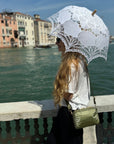 Woman standing near Italian waterfront wearing shimmer olive green mini puffer purse
