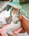 Woman sitting on boat with a beige and green stars zip wristlet on wrist