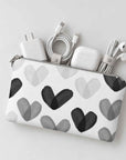 Mini zip pouch with black and white heart print containing various tech items on light gray background.