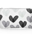 A small zippered pouch with a white background and a pattern of overlapping hand-painted hearts in various shades of gray and black.