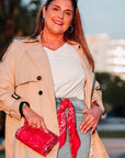 Woman in beige trench coat holding a red bandana pouch with a bandana, outdoors.