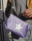Person holding a purple pouch with a white star design.