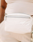 Woman wearing shimmer white puffer fanny pack across waist