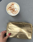 Gold puffer mini clutch on table next to a cup of coffee