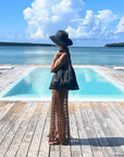 Woman standing in front of an oceanside pool holding a shimmer black puffer tote purse