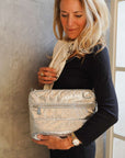 Woman holding a silver clutch against a textured wall