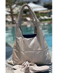 Shimmer beige puffer tote and beige sandals sitting on edge of pool