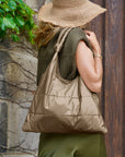 Woman in olive green dress with shimmer bronze puffer handbag over shoulder