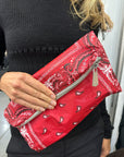 Woman holding a red bandana pattern folded clutch